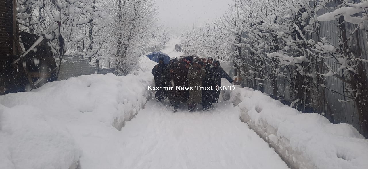 Amid snowfall, local Muslims walk on foot to shoulder the dead body of a Pandit stuck in an ambulance in South Kashmir
